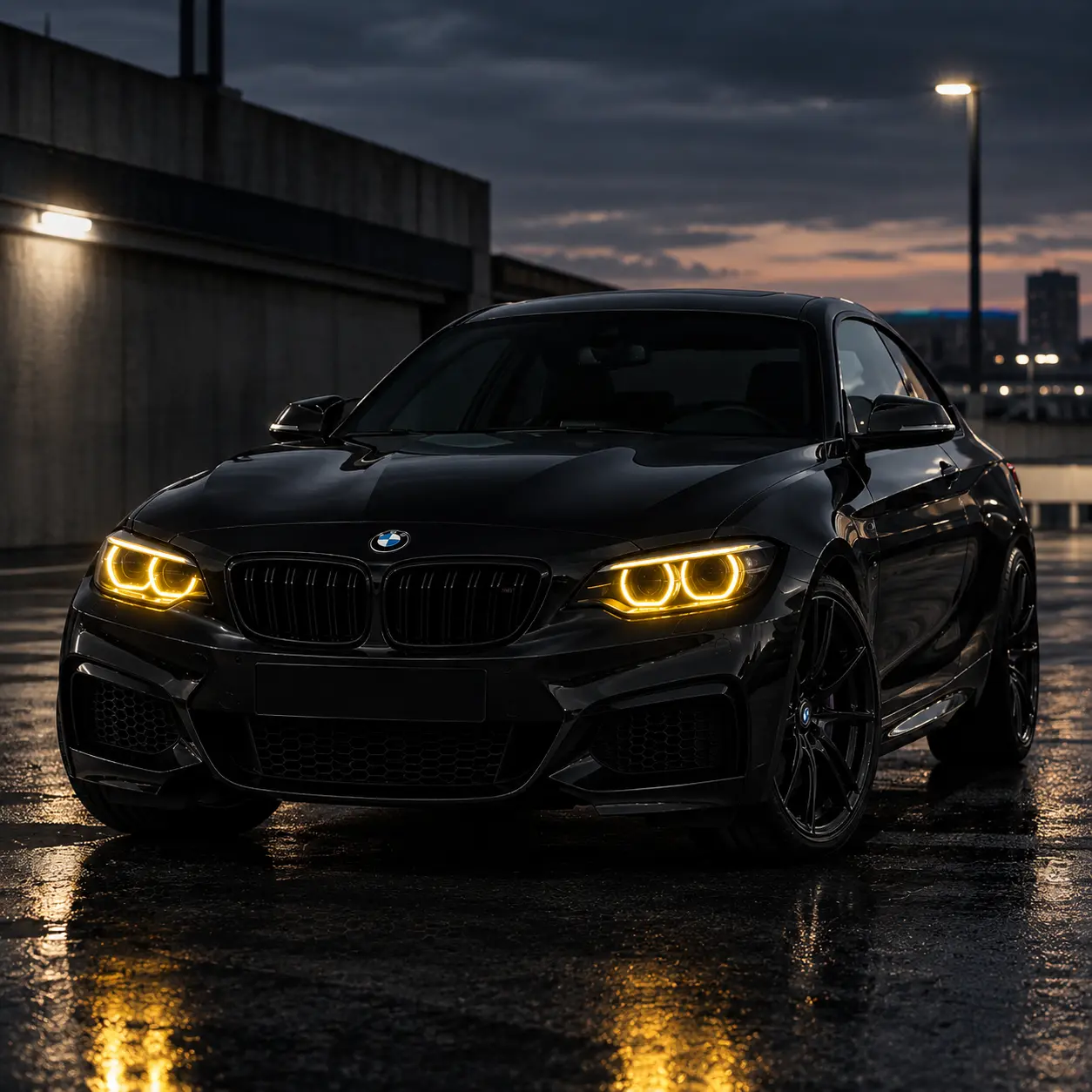 BMW Série 2 F22 noire vue de face en trois-quarts, avec feux LED jaunes allumés dans un environnement urbain de nuit.